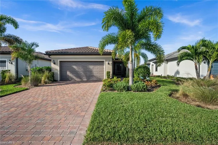 View of front of home with decorative driveway, stucco siding, a garage, and a tiled roof