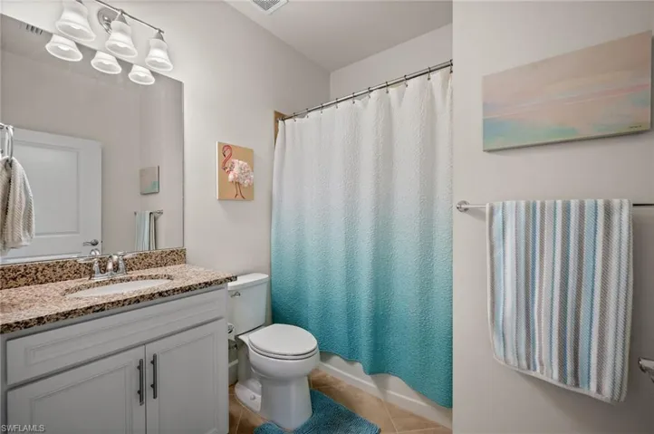 Full bath featuring vanity, light tile patterned flooring, and shower / tub combo