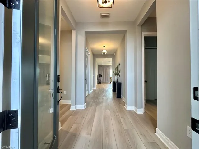 Hallway with light wood-type flooring and baseboards