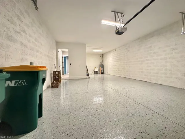 Garage featuring concrete block wall, water heater, and a garage door opener