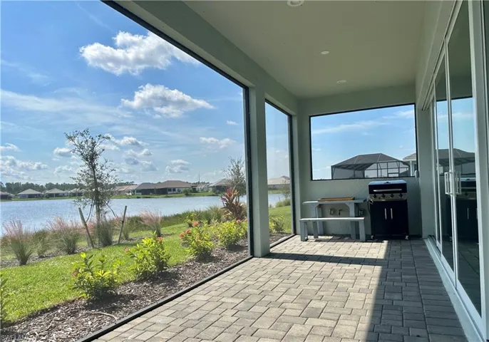 Unfurnished sunroom with a residential view, brick patterned floors, and a water view