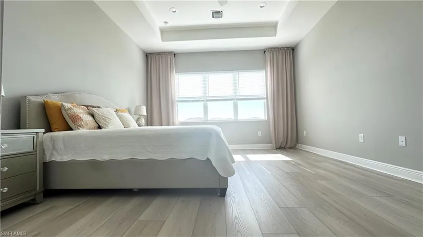 Bedroom with a raised ceiling and light wood finished floors