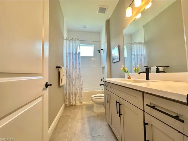 Bathroom featuring shower / bath combination with curtain and vanity