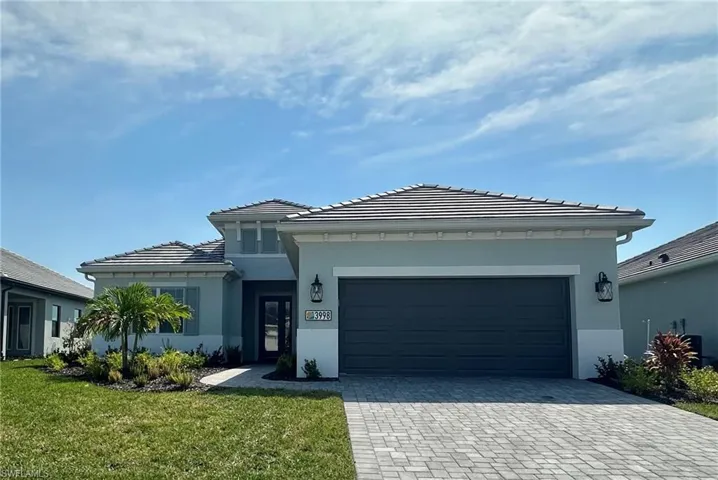 Prairie-style home featuring a tiled roof, a front yard, decorative driveway, stucco siding, and a garage