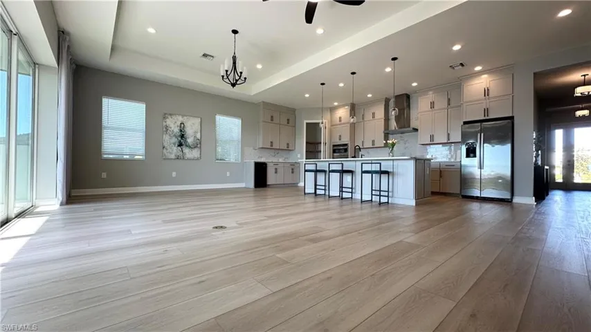 Kitchen featuring appliances with stainless steel finishes, light countertops, a kitchen breakfast bar, backsplash, and recessed lighting