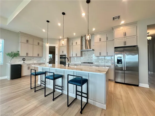 Kitchen featuring stainless steel appliances, decorative backsplash, light stone countertops, and recessed lighting