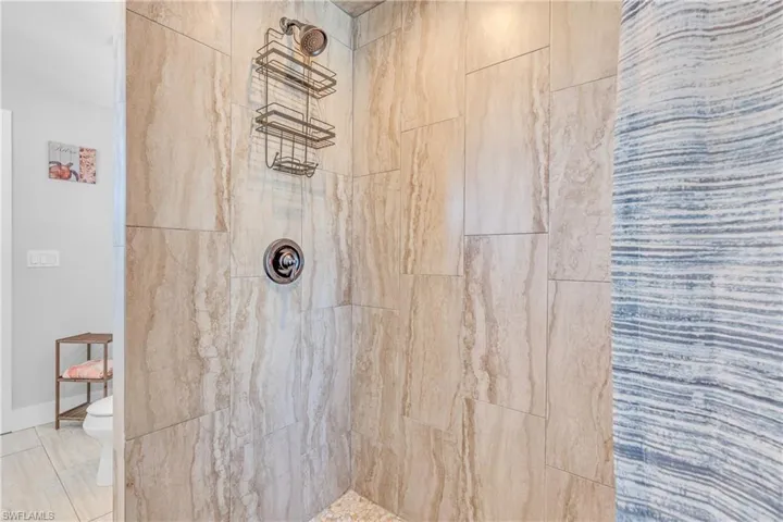 Full bathroom featuring tiled shower and toilet