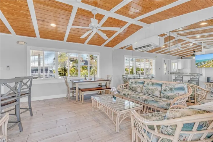 Living area with vaulted ceiling with beams, wood ceiling, healthy amount of natural light, a ceiling fan, and wood tiled floors