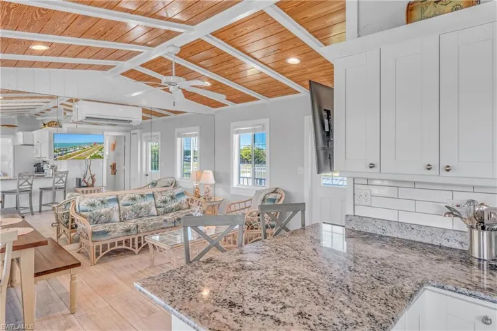 Kitchen featuring wood ceiling, light stone counters, tasteful backsplash, white cabinets, and a peninsula