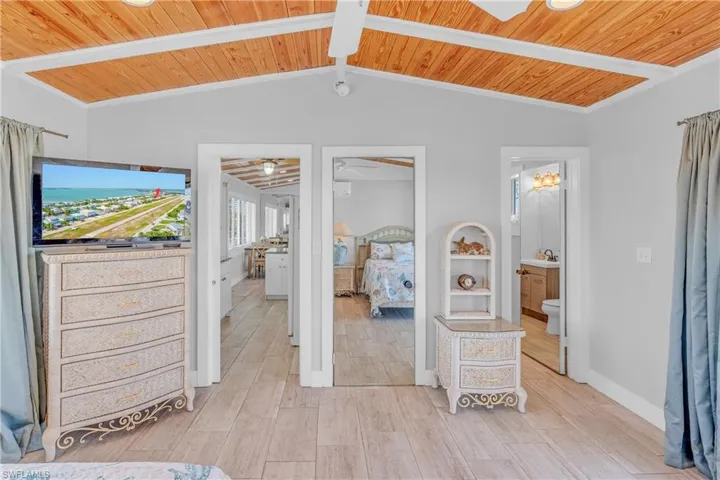 Bedroom featuring ensuite bath, wooden ceiling, and light wood finished floors