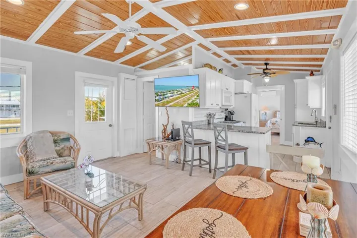 Living area with a ceiling fan, lofted ceiling with beams, wood ceiling, light wood-style floors, and recessed lighting