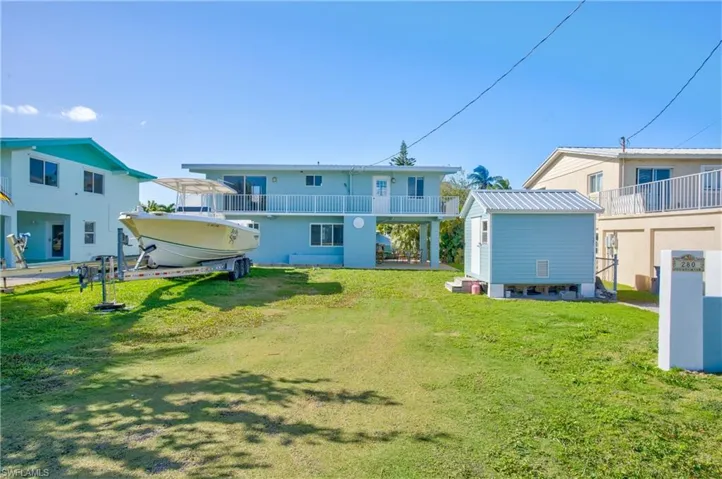 Back of house featuring a balcony and a yard