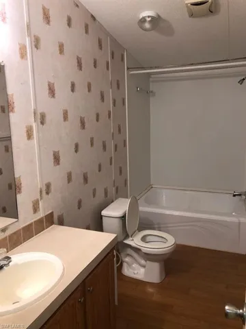 Full bathroom featuring vanity, shower / bath combination, a textured ceiling, wood-type flooring, and toilet