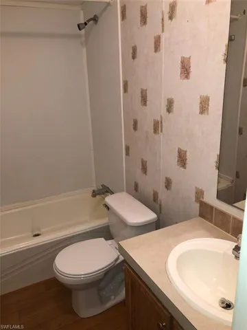 Full bathroom with hardwood / wood-style floors, toilet, shower / tub combination, and vanity