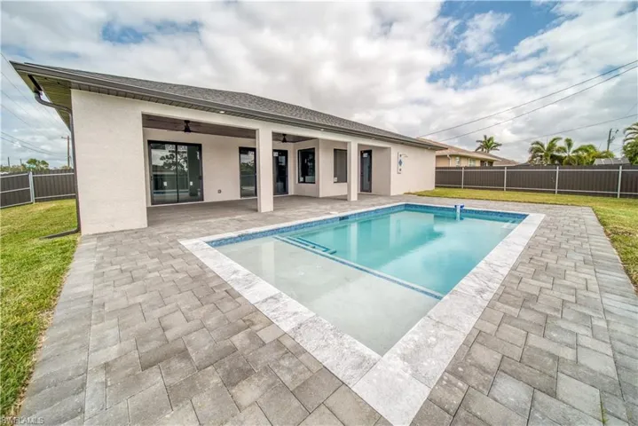 View of pool with ceiling fan, a patio, and a lawn