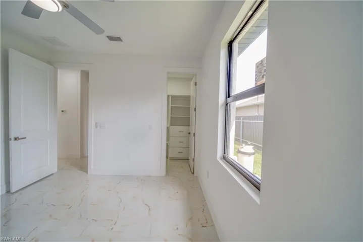 Unfurnished bedroom with a spacious closet, a closet, and ceiling fan