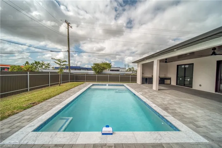 View of swimming pool featuring a patio area, ceiling fan, and exterior kitchen
