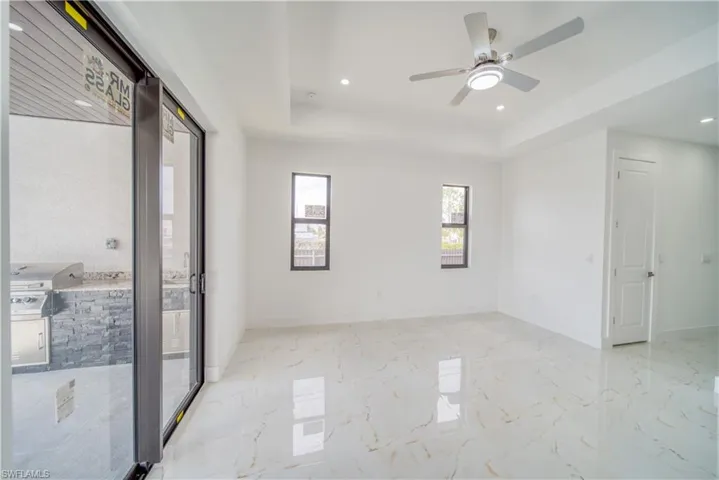 Empty room with ceiling fan and a tray ceiling