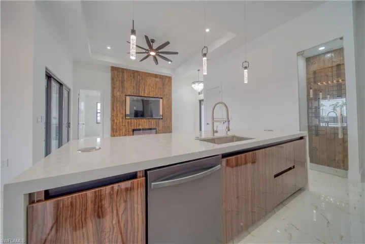 Kitchen with pendant lighting, sink, a tray ceiling, and dishwasher