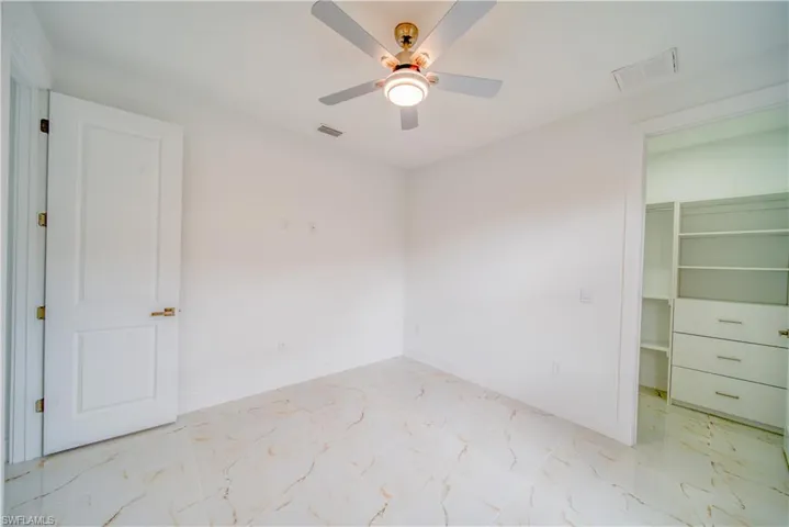 Unfurnished bedroom featuring ceiling fan, a walk in closet, and a closet