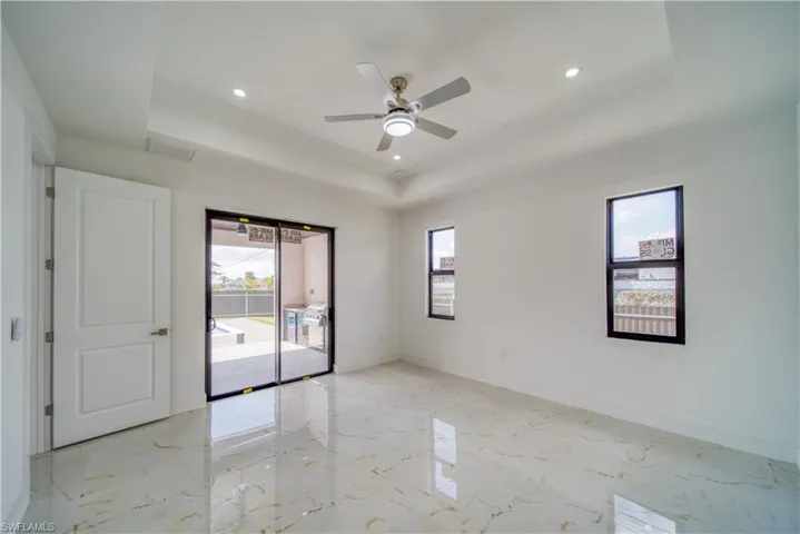 Empty room featuring a wealth of natural light, a raised ceiling, and ceiling fan
