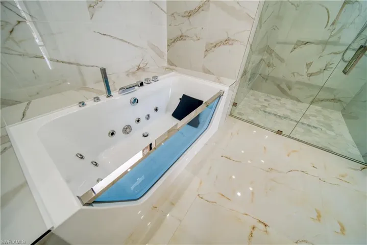 Bathroom featuring tile walls and separate shower and tub