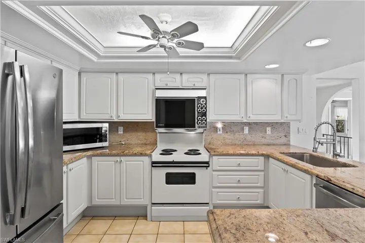Kitchen with crown molding, newer stainless steel fridge, tasteful backsplash, and ceiling fan.
