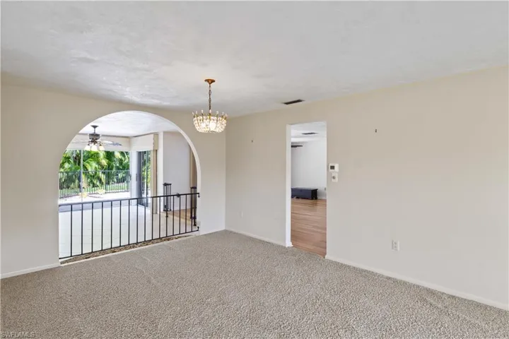 Spare room featuring carpet flooring and ceiling fan with notable chandelier