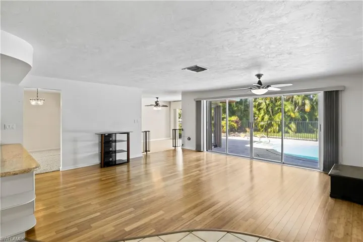Living room with beautiful hardwood floors, sliders to the outside - the home was designed with lots of windows and doors to allow the natural light in!  PGT windows in 2009 and hurricane impact accordion shutters on doors in 2015!