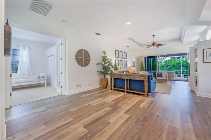 Living room with ceiling fan, a tray ceiling, and hardwood / wood-style flooring