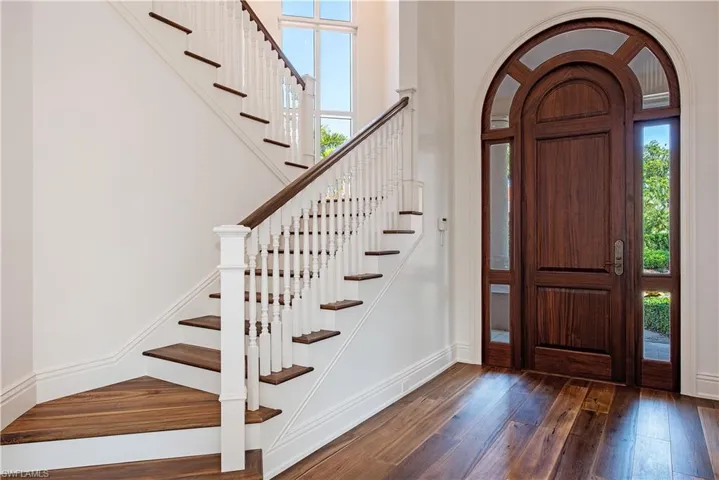 Foyer with plenty of natural light, stairs and dark wood floors