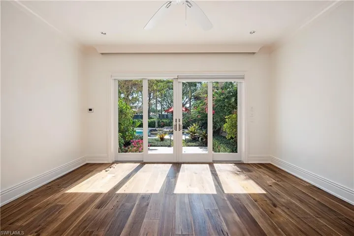 Bedroom featuring dark hardwood flooring, crown molding, ceiling fan, and sliding doors to patio
