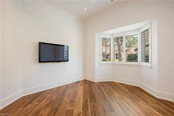 Office with dark wood finished floors and crown molding