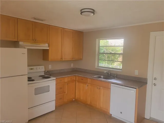 Kitchen featuring white appliances, light tile patterned flooring, and ornamental molding