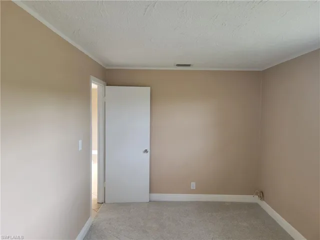Unfurnished room featuring light carpet, crown molding, and a textured ceiling
