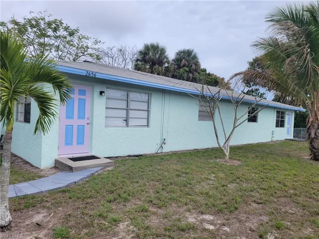 Back of property featuring a lawn and stucco siding