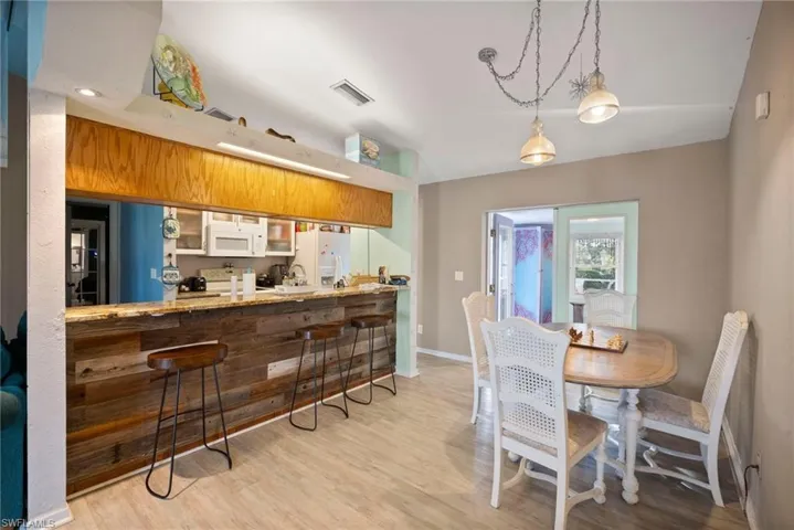 Kitchen featuring kitchen peninsula, white appliances, light hardwood / wood-style floors, and hanging light fixtures