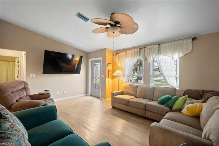 Living room featuring ceiling fan, light hardwood / wood-style flooring, and lofted ceiling