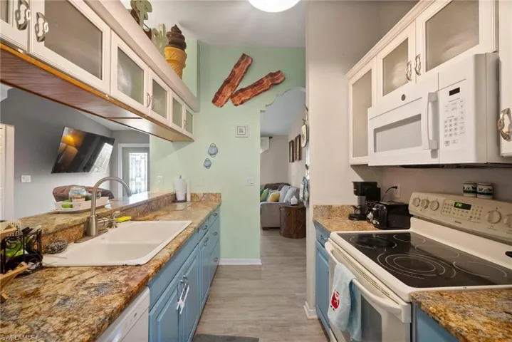 Kitchen featuring white cabinetry, sink, blue cabinets, light hardwood / wood-style floors, and white appliances
