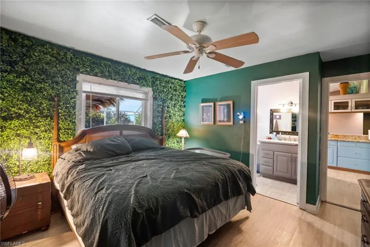 Bedroom featuring ceiling fan, light hardwood / wood-style flooring, and ensuite bath