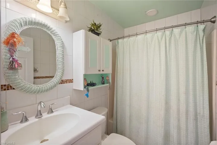 Bathroom with toilet, tile walls, and sink