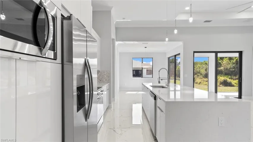 Kitchen with marble finish floor, appliances with stainless steel finishes, white cabinets, a sink, and modern cabinets