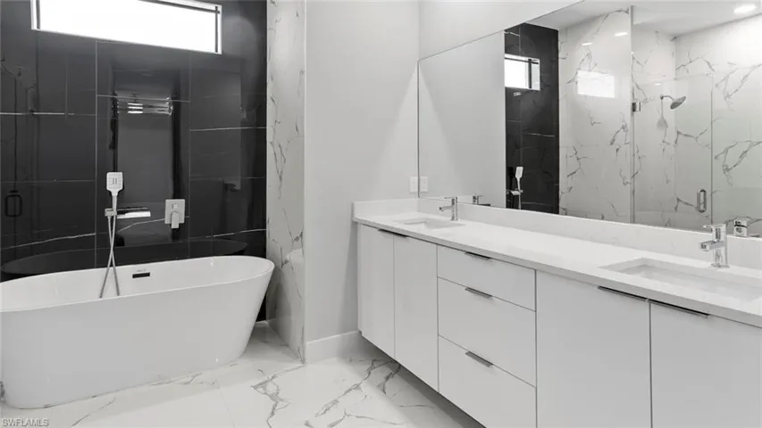 Bathroom with marble finish floor, a sink, a marble finish shower, and double vanity