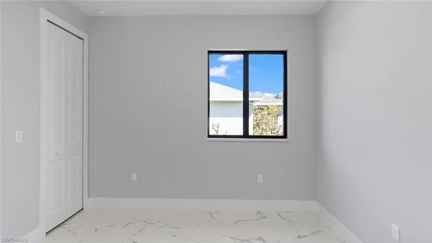 Unfurnished bedroom with marble finish floor, baseboards, and a closet