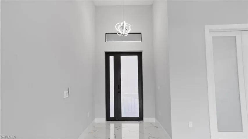 Entryway with marble finish floor, baseboards, and an inviting chandelier