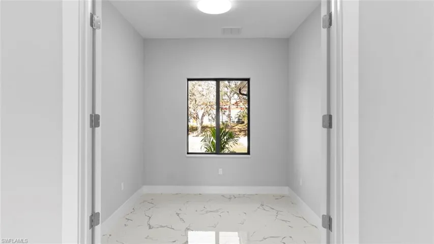 Empty room featuring marble finish floor, visible vents, and baseboards