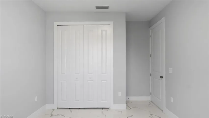 Unfurnished bedroom featuring marble finish floor, a closet, visible vents, and baseboards