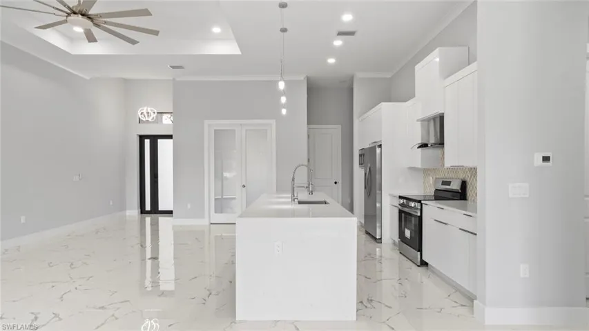 Kitchen featuring a sink, visible vents, white cabinets, appliances with stainless steel finishes, and a center island with sink