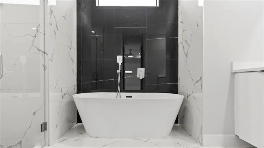 Bathroom with marble finish floor and a freestanding bath