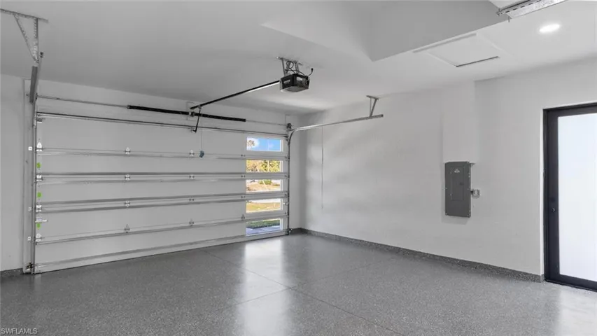 Garage with electric panel, baseboards, and a garage door opener